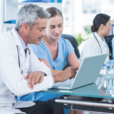 Doctors discussing patient information on a laptop.